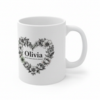 White ceramic mug with floral heart wreath and “Olivia” on front