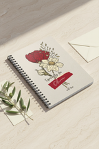 A5 floral journal notebook on tabletop, beige cover with floral art and red name tag