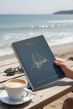 Blue A5 spiral notebook with OLIVIA name and sailboat line drawing on cover.