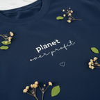 Dark navy sweatshirt close-up of chest print: 'planet over profit' with heart