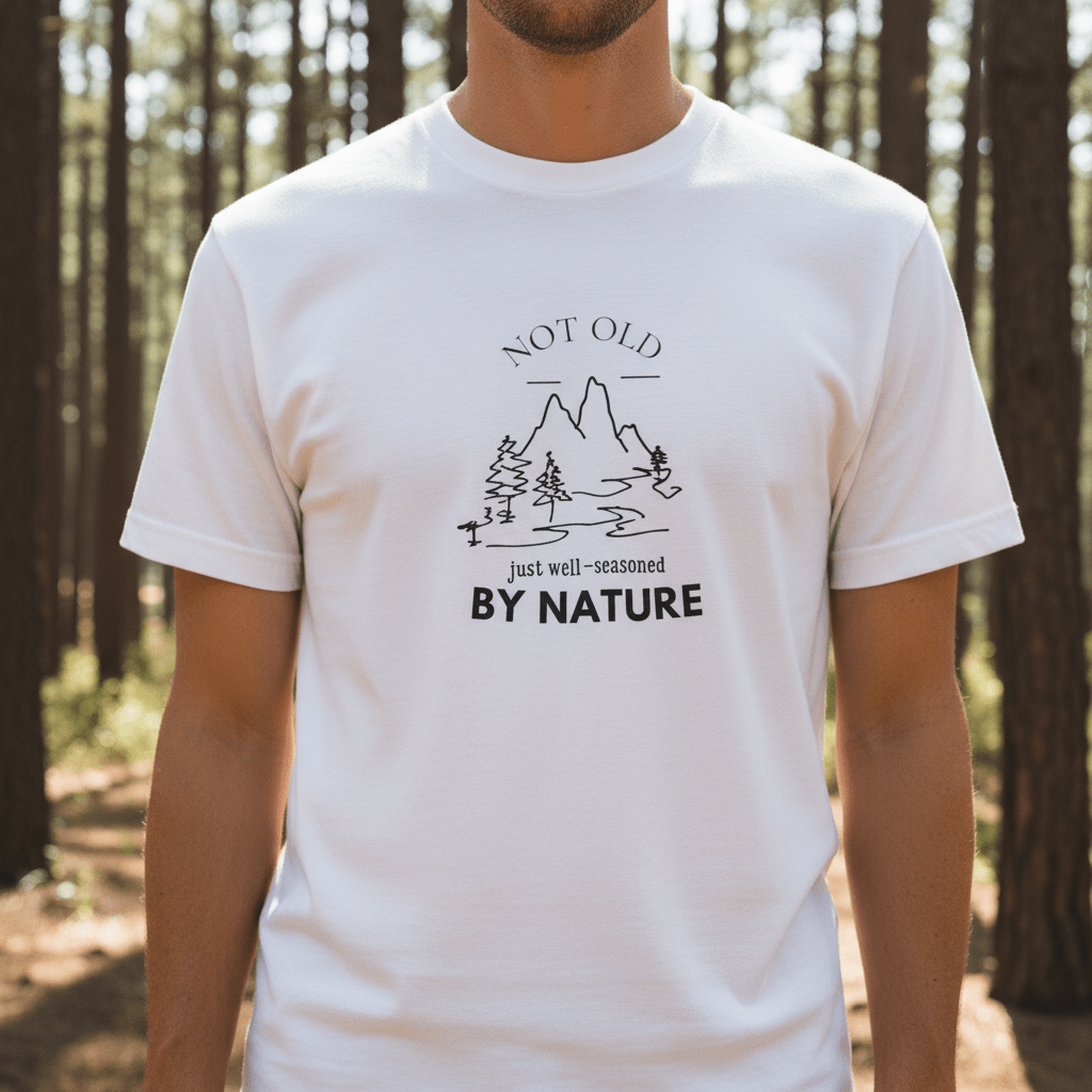 White graphic T-shirt with centered mountain and trees logo and “BY NATURE” text