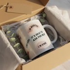 White ceramic mug in an open box with “IT’S OKAY TO ASK FOR HELP” and “I’M KIND”