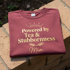 Pink T-shirt with gold “Powered by Tea & Stubbornness” and “Mum”