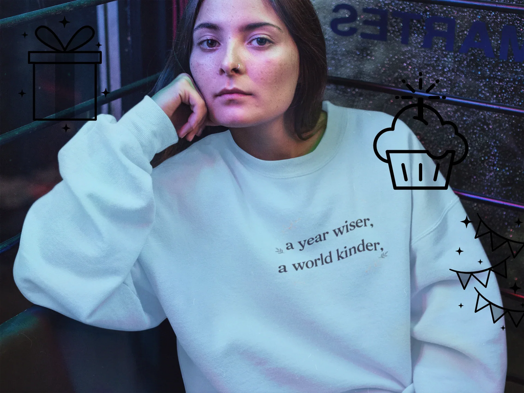 White crewneck sweatshirt with "a year wiser, a world kinder" text print