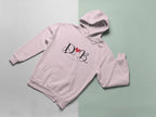 Pale pink hoodie with heart monogram graphic on chest, folded view with hood