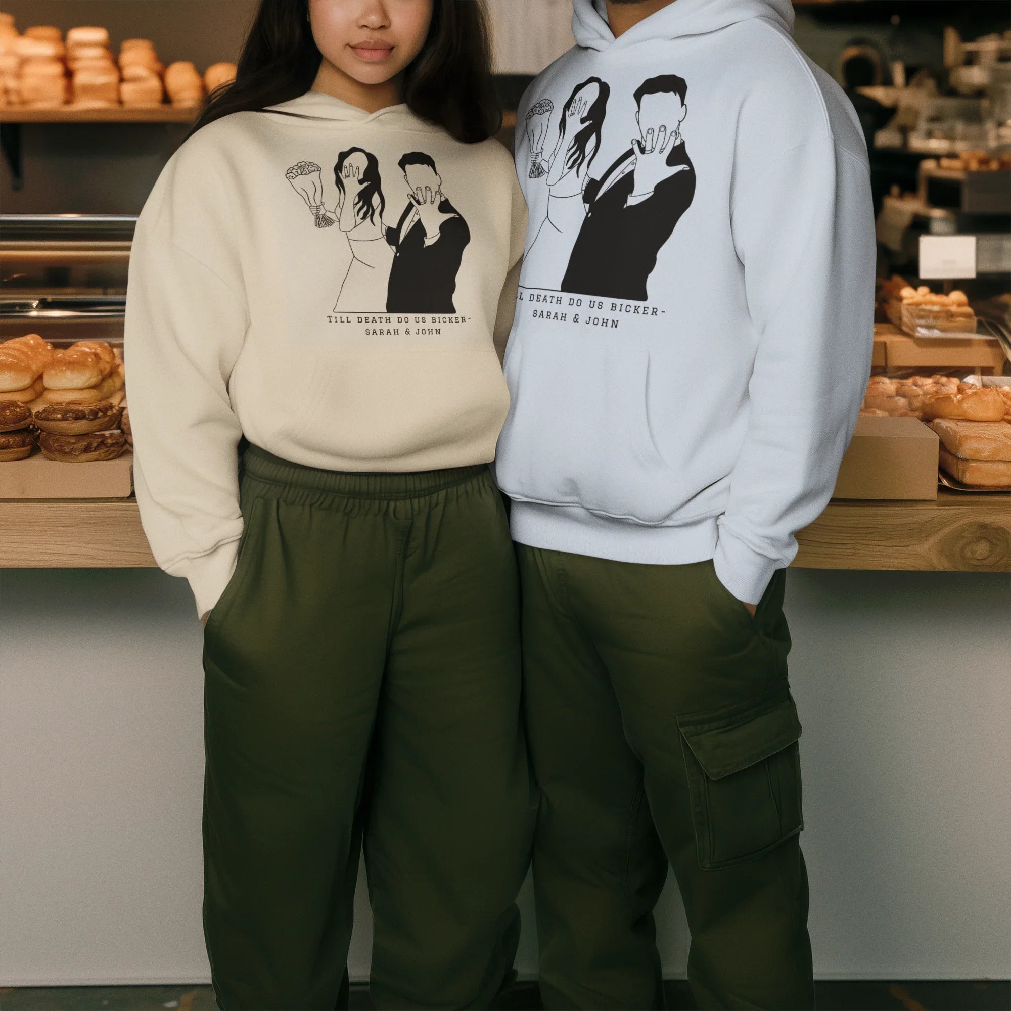 White and light-blue couple graphic hoodies worn together, with front prints and cuffs.