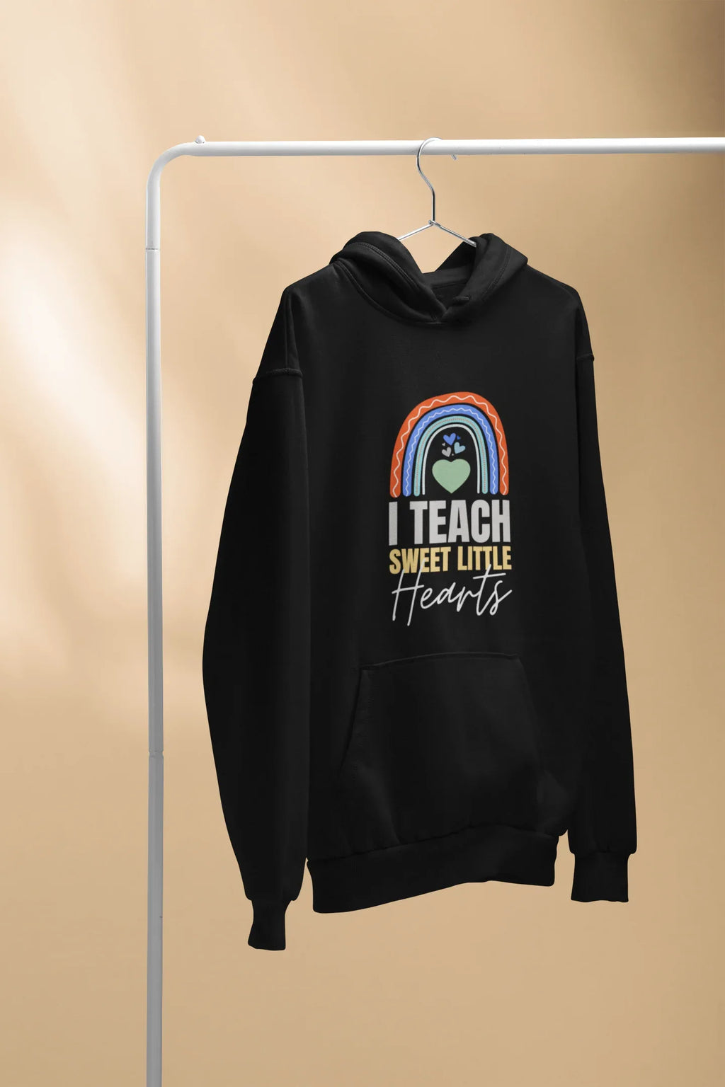 Black unisex pullover hoodie on hanger with kangaroo pocket and front “I TEACH SWEET LITTLE Hearts”