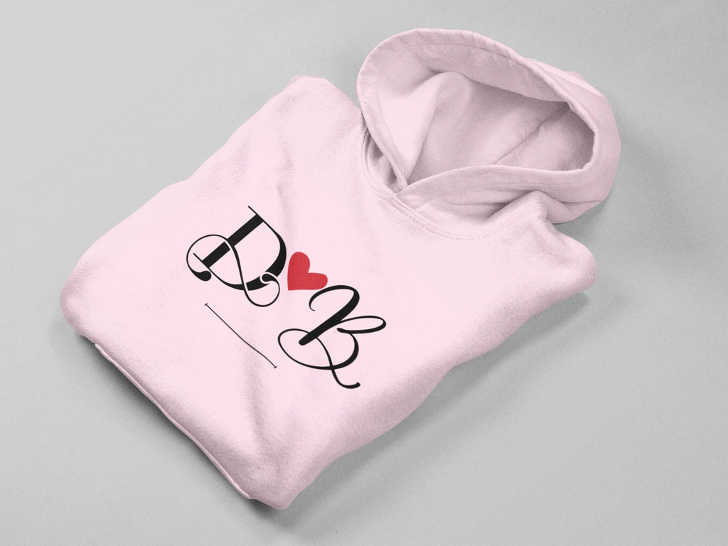 Light pink hoodie with heart monogram graphic on front, folded view