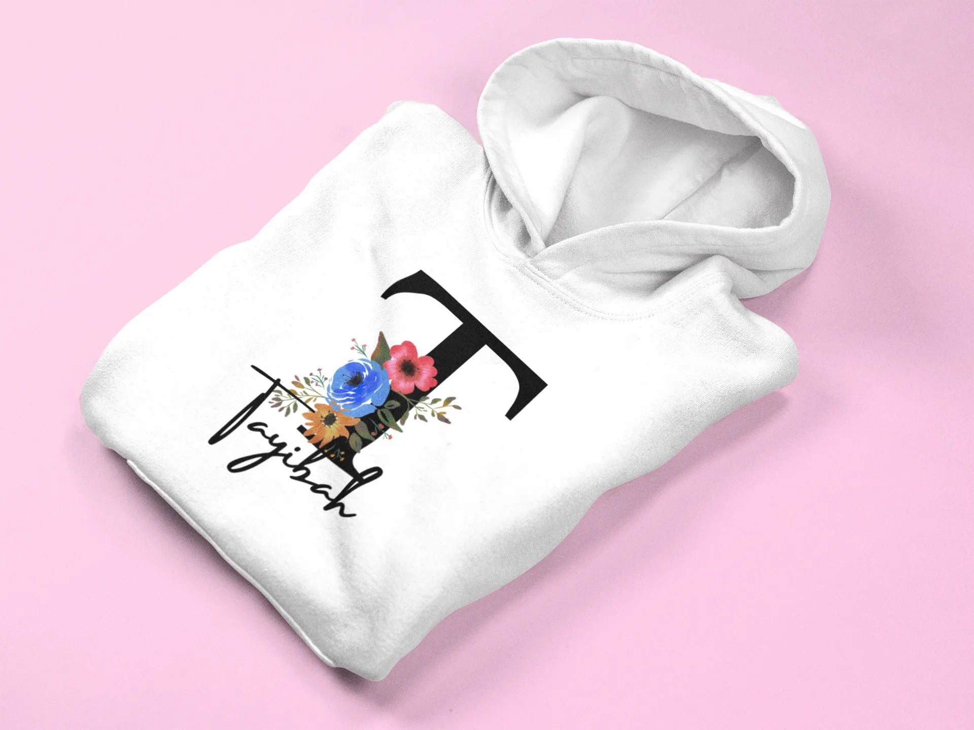 White kids hoodie close-up with hood, floral letter and script name graphic on front