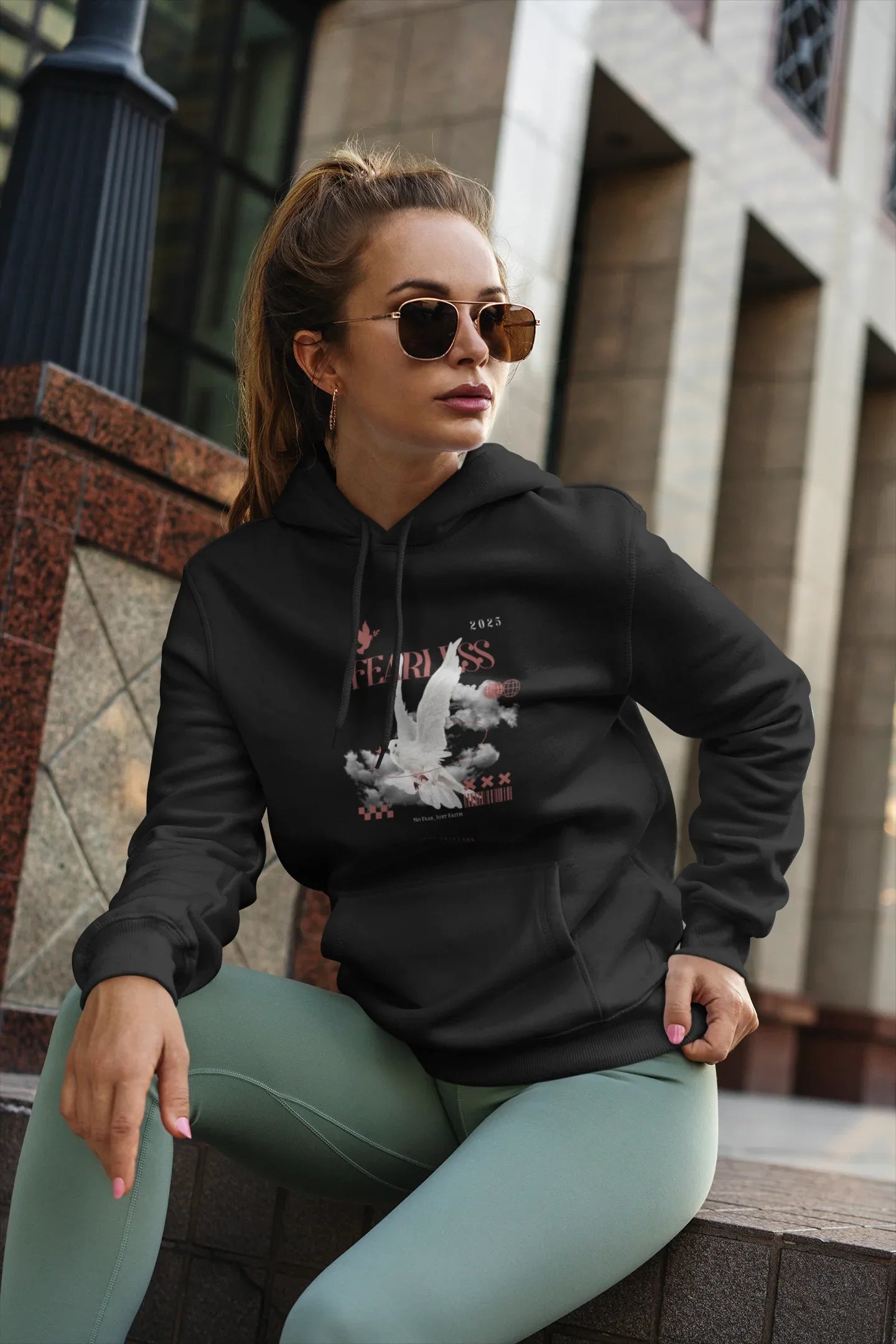 Black unisex hoodie with hood and chest graphic, model seated