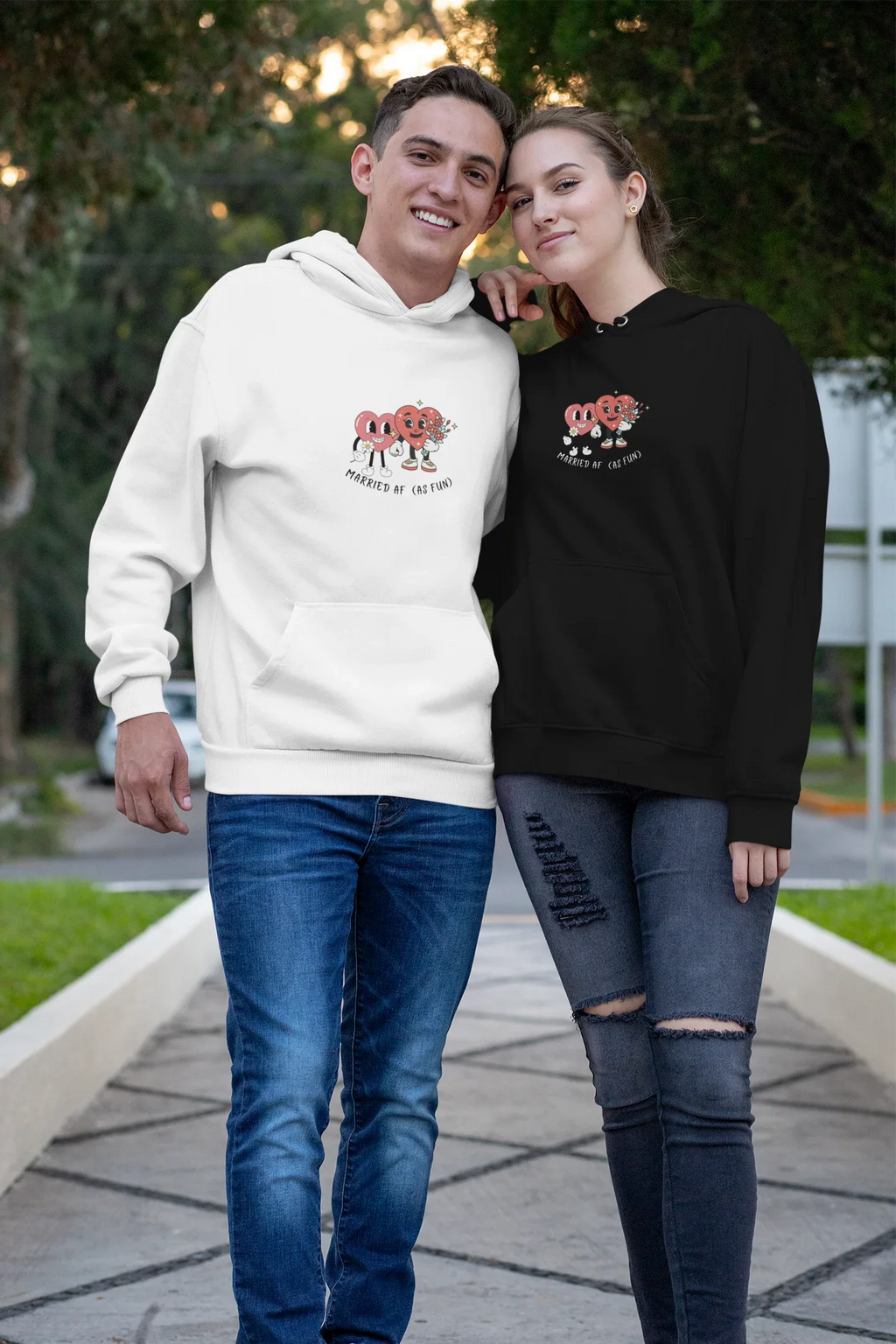 White and black hoodies worn by a couple, heart cartoon logo on each chest