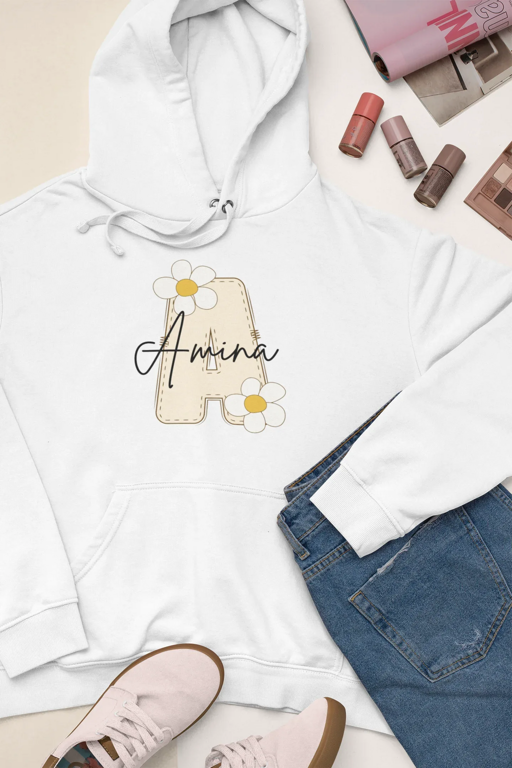 Kids white hoodie detail with hood and front pocket; floral name graphic on chest
