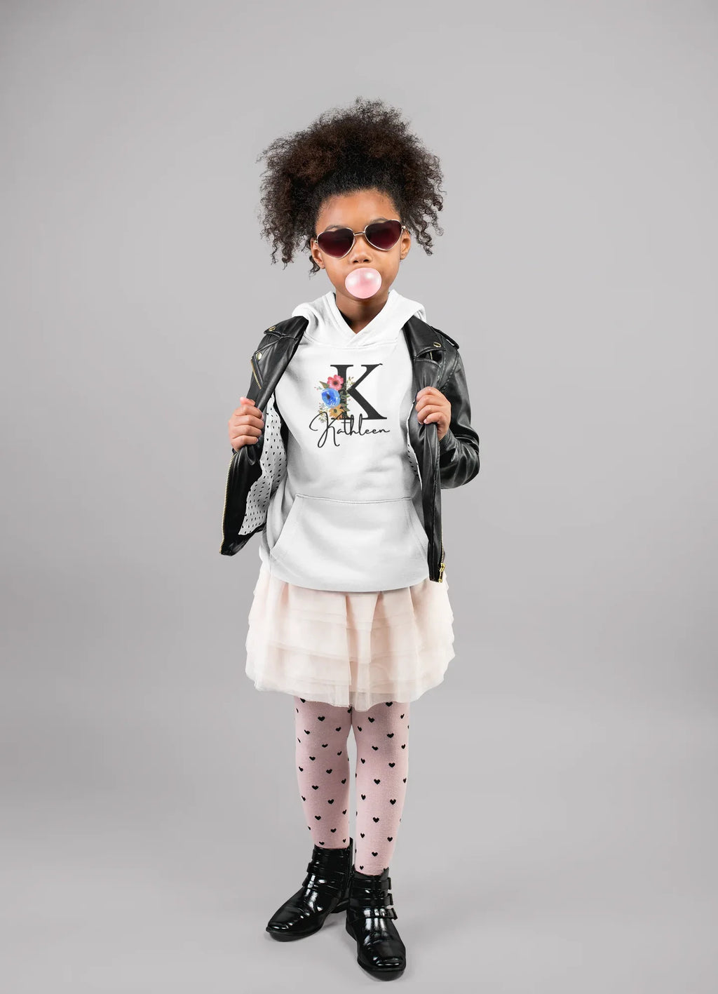 White kids hoodie on a child, floral letter and script name graphic centered on chest