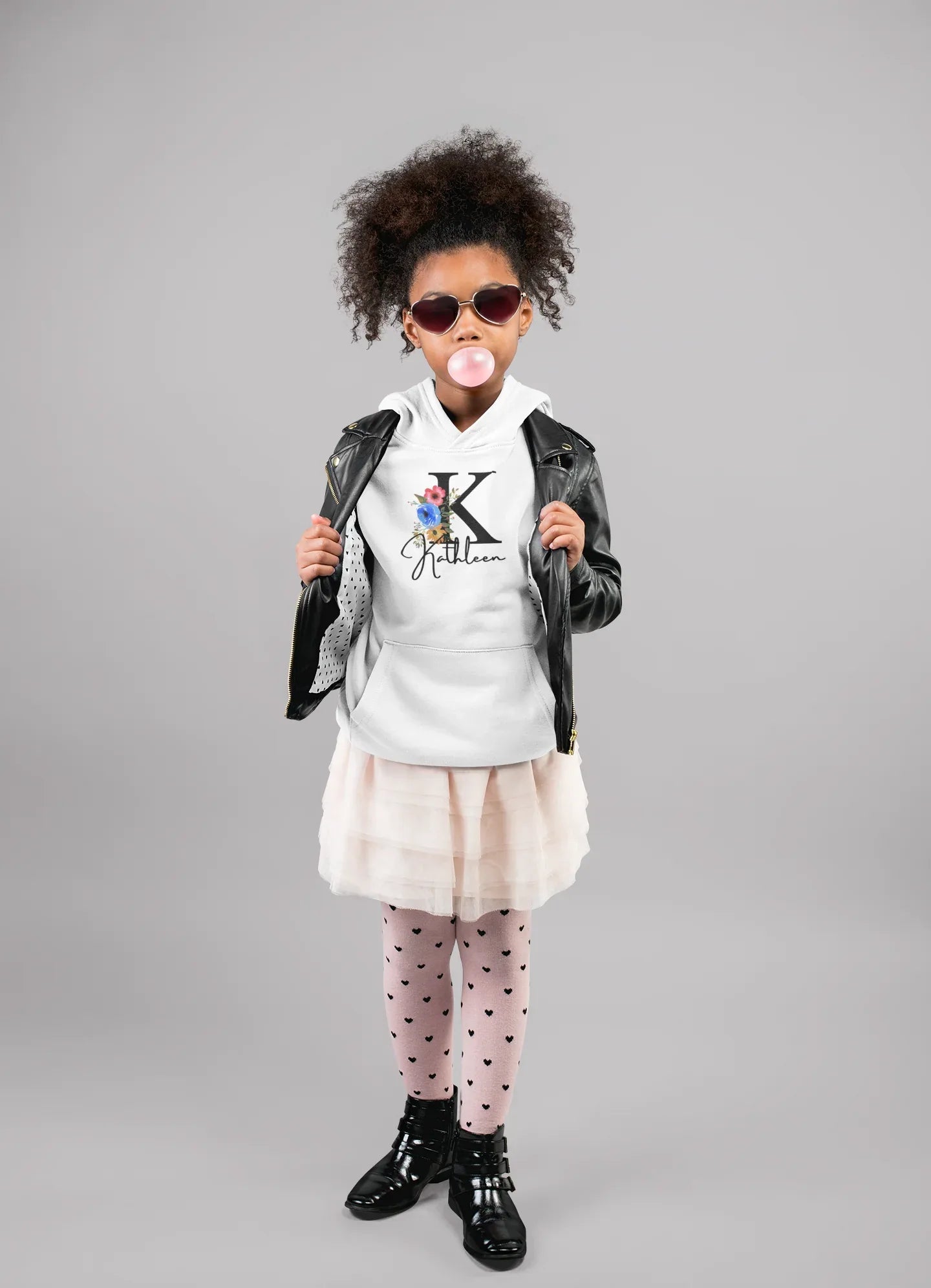 White kids hoodie on a child, floral letter and script name graphic centered on chest