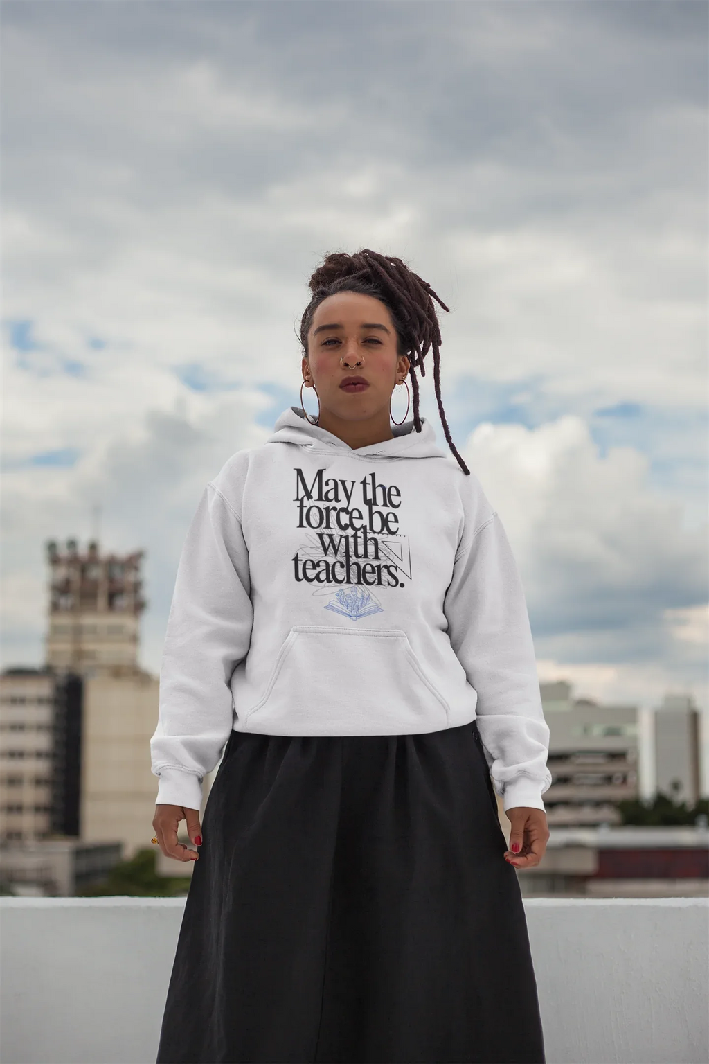 White hooded sweatshirt with front graphic text and blue book emblem, worn outdoors.