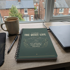 Quiet Life notebook beside a laptop and tea