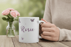 White mug with purple butterfly print and name Rosie, held in a hand