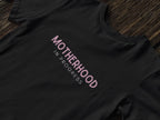 Maternity heavy cotton tee in black with pink “Motherhood in Progress” logo print