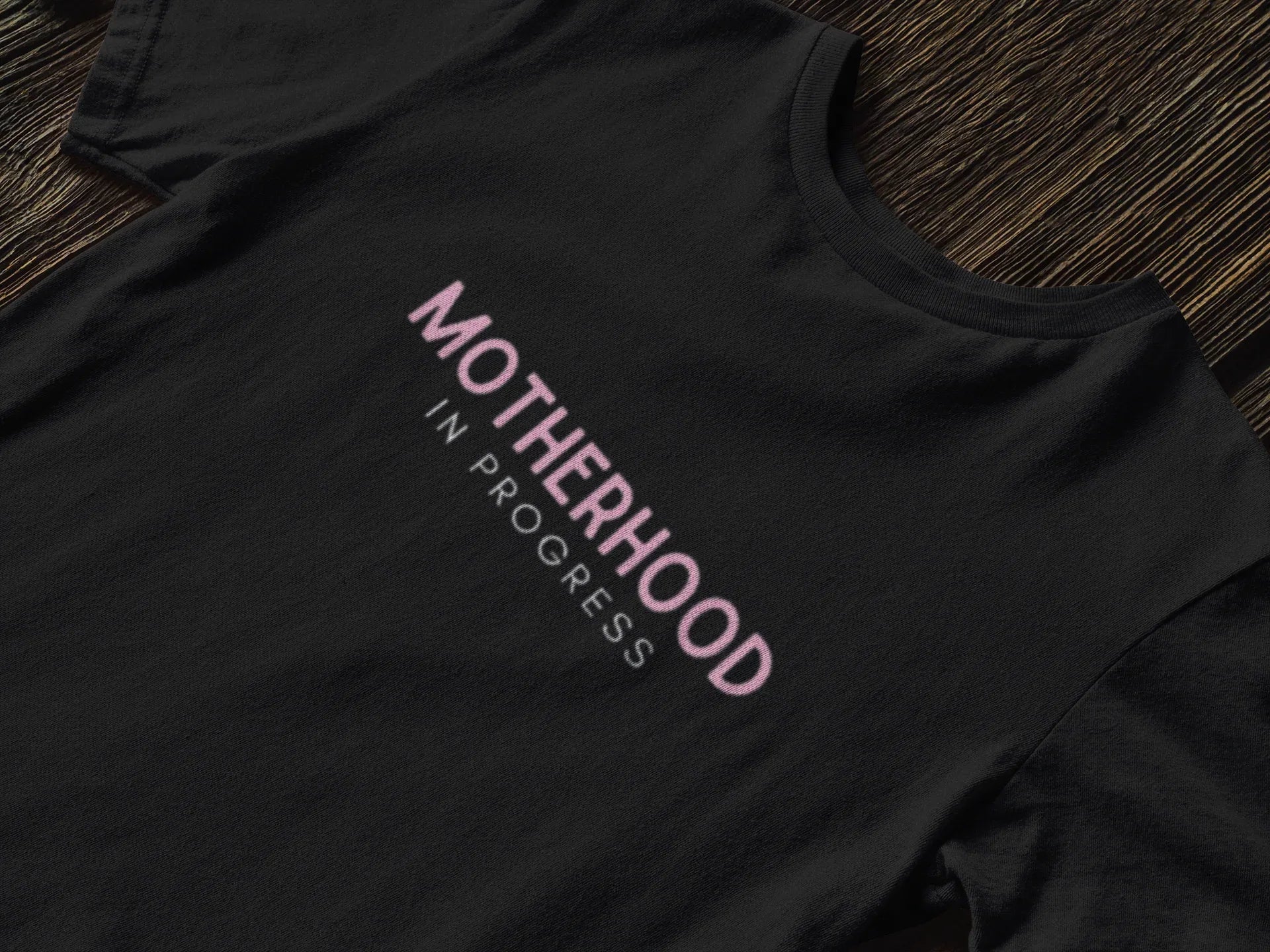 Maternity heavy cotton tee in black with pink “Motherhood in Progress” logo print