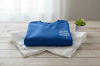 Folded blue crewneck sweatshirt with small chest logo