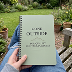 Sage green notebook held on a garden bench
