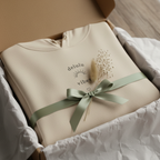 Beige hoodie in a gift box with light green ribbon bow and small chest slogan print