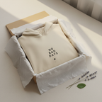 Beige hooded sweatshirt folded in gift box with drawstring hood and graphic