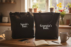 Pair of black cotton tote bags with text “Sarah's Tote.” and “Georgia's Tote.”