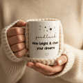 Hands holding white ceramic mug with “goodluck” and “shine bright & chase your dreams”
