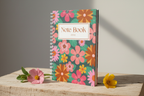 Side view of notebook standing with flowers at base
