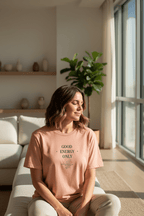 Peach T-shirt worn by a person, with 'Good Energy Only' chest graphic