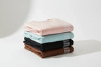 Stacked crewneck sweatshirts in blush, light blue, black, and brown