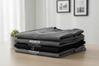 Stack of dark gray crew-neck T-shirts with “Progress” and small plant graphic