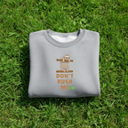 Grey crewneck sweatshirt folded, with sloth graphic and 'Don't Rush Me' front print