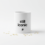 Ceramic coffee mug with “still iconic” text and star on white