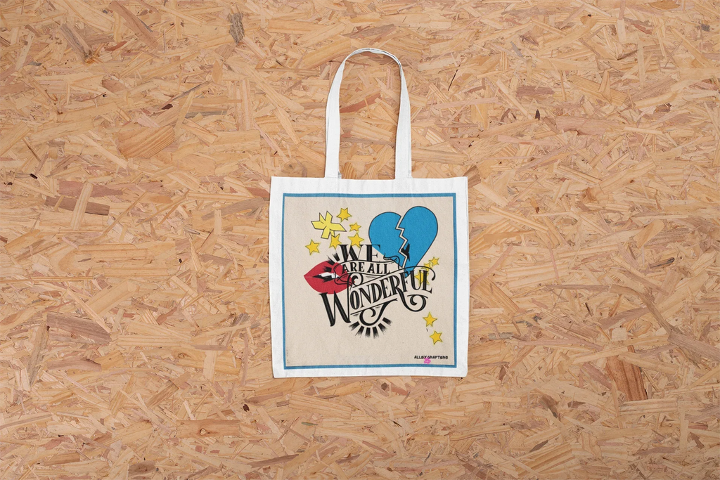 Beige canvas tote bag with blue and yellow graphic heart and text