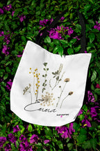 White canvas tote bag with botanical flower print and cursive "Anna" wordmark