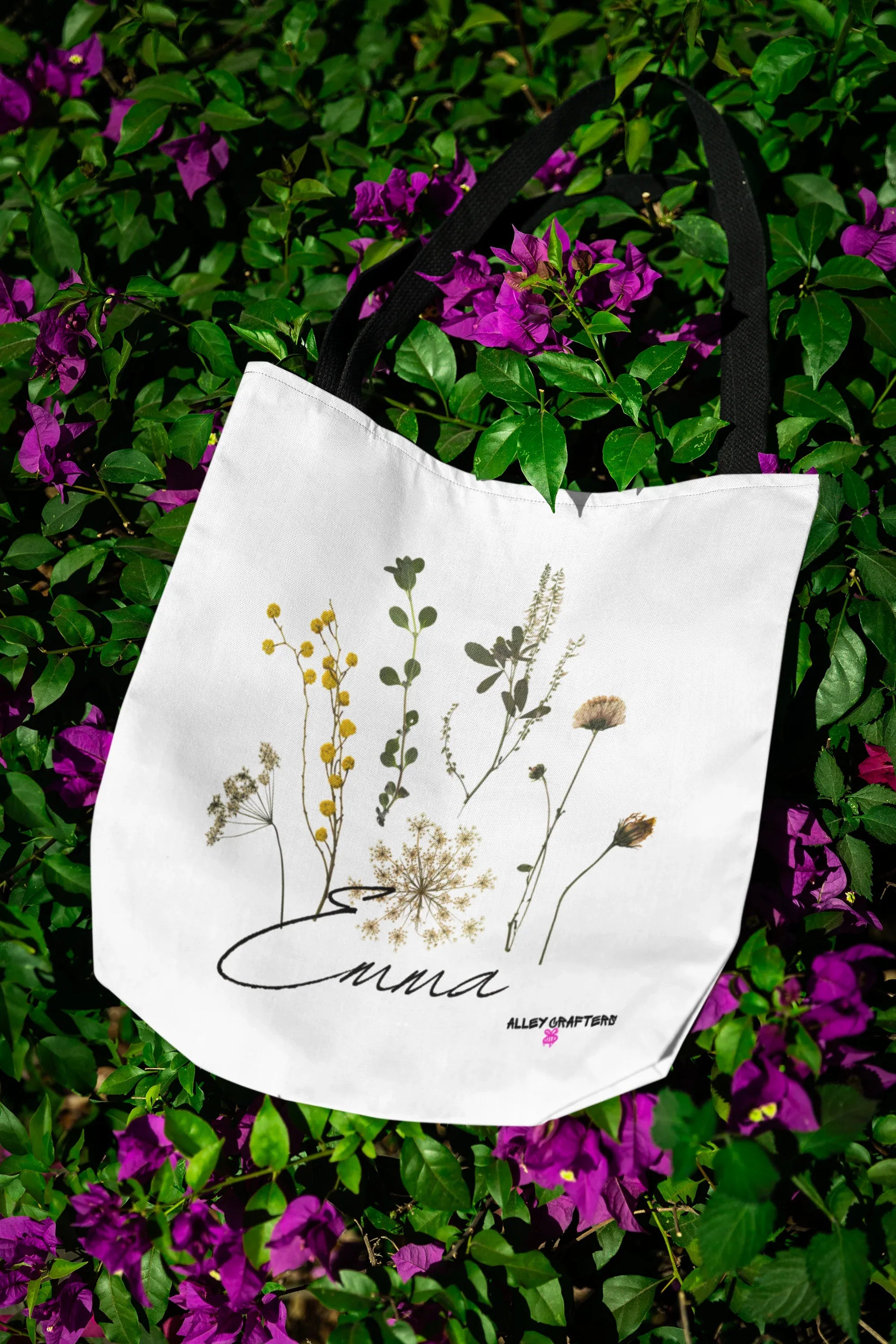 White canvas tote bag with botanical flower print and cursive "Anna" wordmark