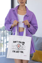 White canvas tote bag showing black "DON'T FOLLOW ME" and "I'M LOST TOO" text