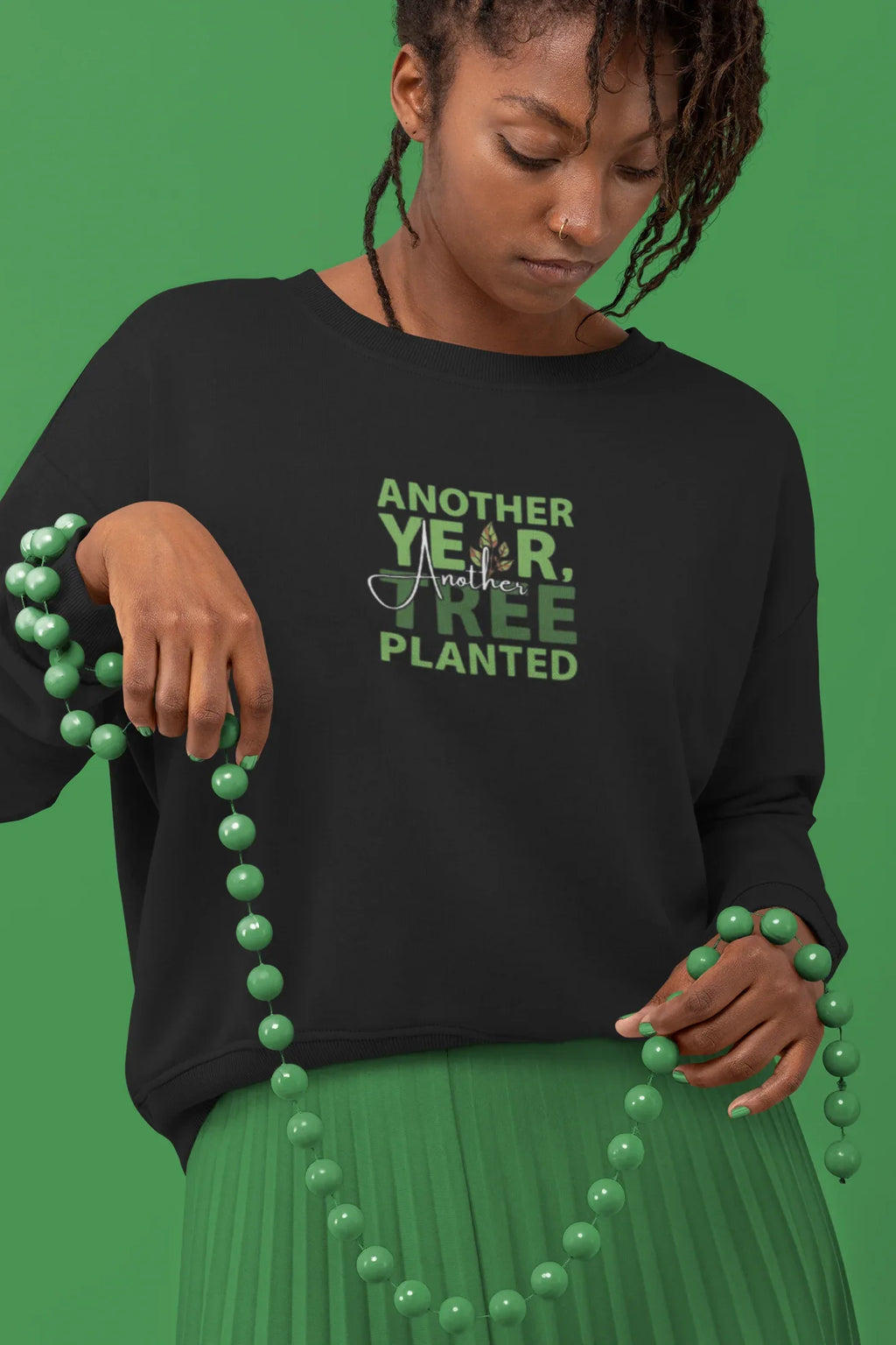 Black crewneck sweatshirt with green “Another Year, Tree Planted” chest graphic.
