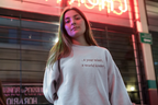 Light gray crewneck sweatshirt with a year wiser, a world kinder text