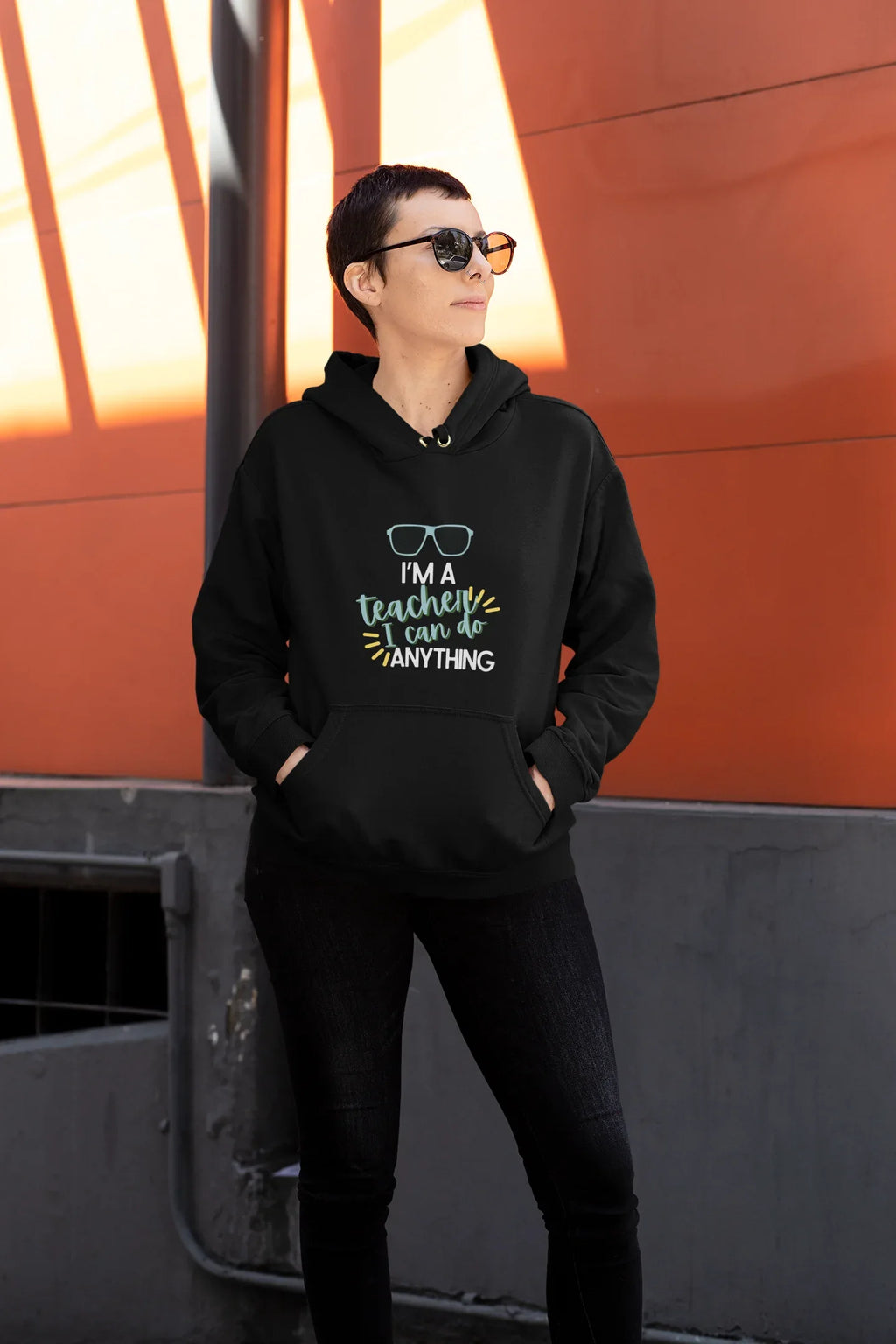 Black unisex hoodie worn by model with hood and front teacher slogan graphic