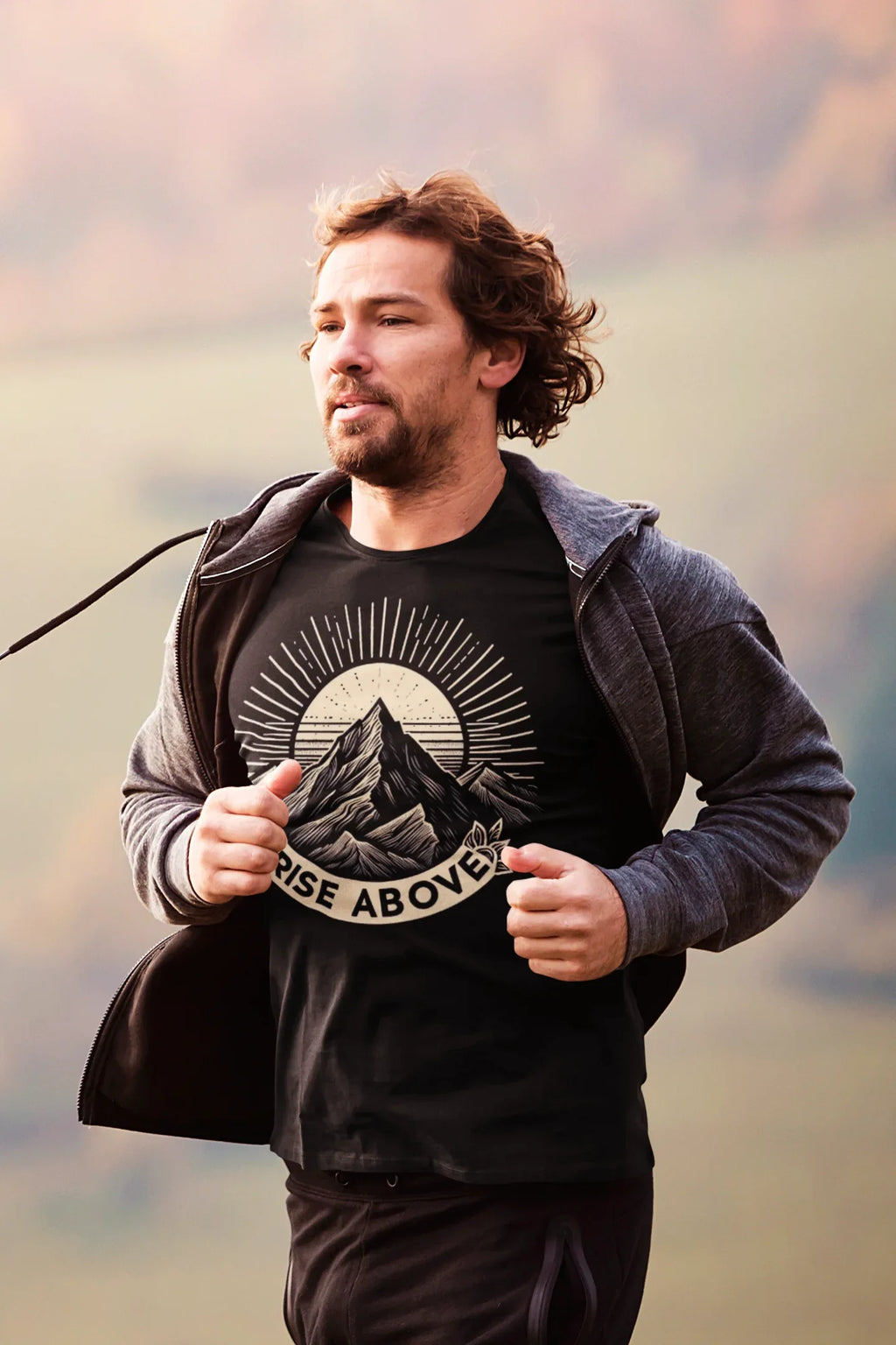 Black graphic T-shirt with mountain sunrise “RISE ABOVE” worn with jacket