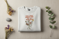 White crewneck sweatshirt with floral quote graphic on front, crew neckline