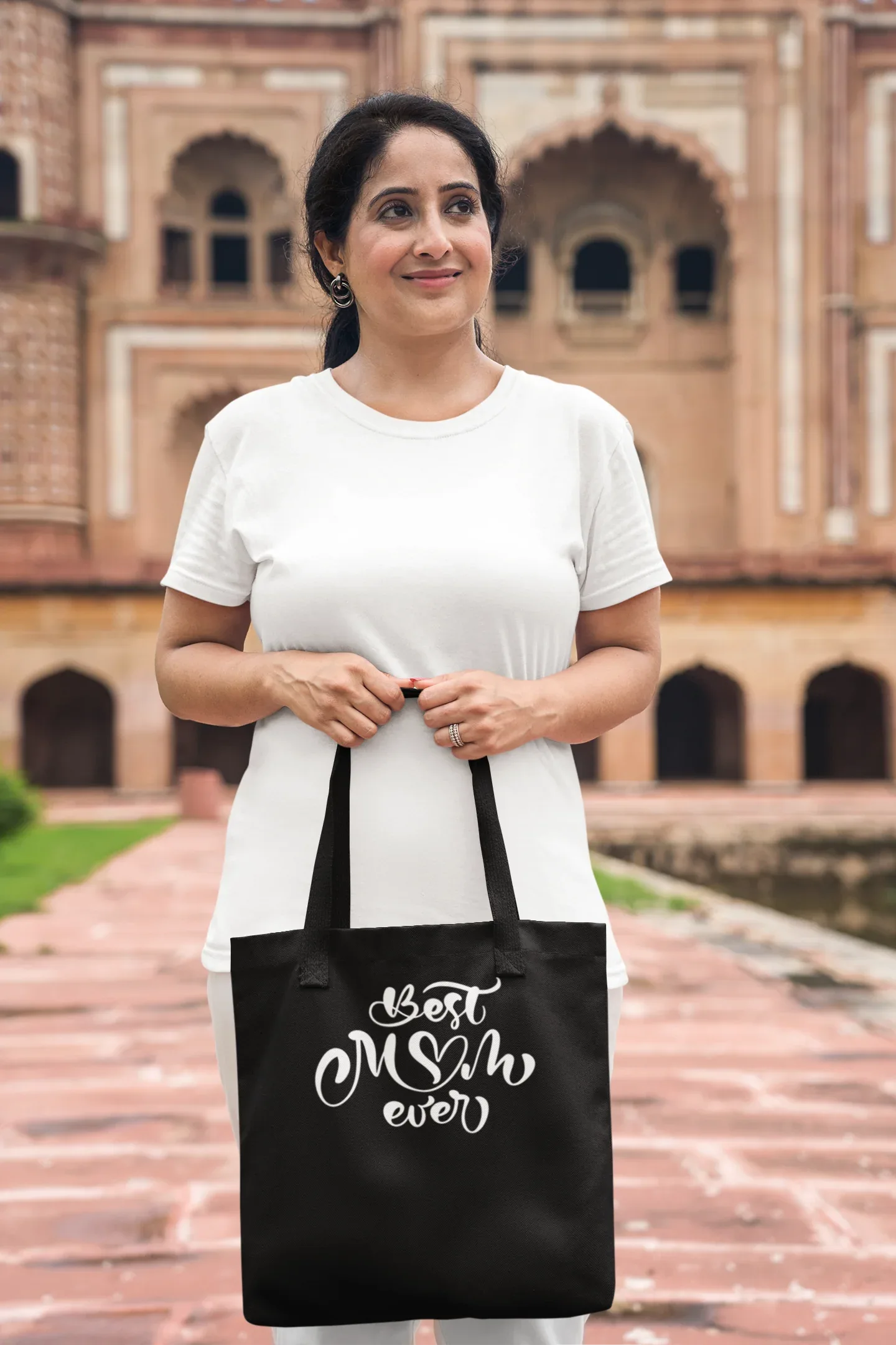 Black canvas tote bag with “Best Mum ever” white lettering, carried by person outdoors