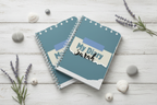 Three diaries stacked with shells and sea lavender