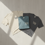 Crewneck Birthday Energy tees in cream, teal, and dark gray with front graphic
