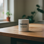 White coffee mug on wooden table with THRIVING (Term dependant) print