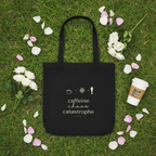 Black tote bag with “caffeine chaos catastrophe” print, surrounded by flowers and a coffee cup.