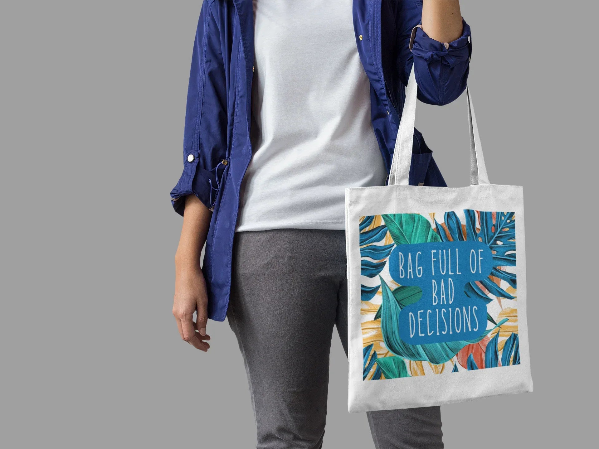 White canvas tote bag with colorful tropical print and teal circular lettering.